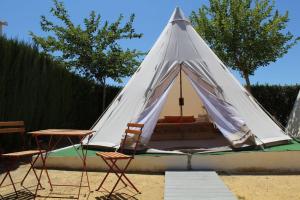 Tienda blanca con 2 sillas y mesa en Casas Rurales el Nogalejo Setenil en Setenil