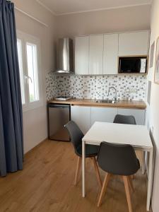 a kitchen with a white table and chairs in a room at AMMOS Beach apartment in Sidari