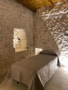 ein Schlafzimmer mit einem Bett in einer Steinmauer in der Unterkunft Casolare 67 in Noci