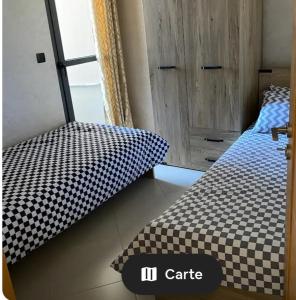 a bedroom with a bed with a black and white checkered bedspread at Appartement neuf in Nador