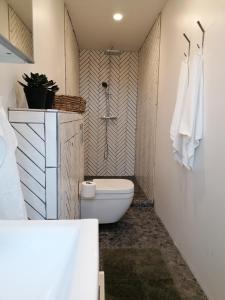 a bathroom with a toilet and a shower with towels at Blackwood cottage near Geysir in Reykholt