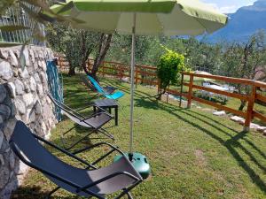 2 chaises et un parasol dans l'herbe dans l'établissement Ulivi sul Garda Garden by Gardadomusmea, à Tremosine