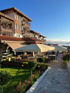 a hotel with tables and umbrellas in a courtyard at Family Hotel The View & SPA in Tsigov Chark