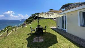 - une table avec un parasol sur le côté d'une maison dans l'établissement Villa Costa Bianca by ArgonautiVacanze, à Portoferraio
