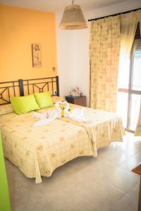 a bedroom with a bed with a blanket and a window at Hostal Malia in Conil de la Frontera