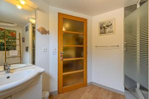 ein Badezimmer mit einem Waschbecken und einer Holztür in der Unterkunft Sous les Palmiers - Charmant Appartement avec terrasse in Vannes
