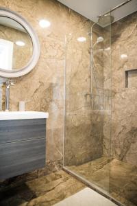 y baño con ducha acristalada y lavamanos. en HARMONY Stay APARTAMENTAI en Telšiai