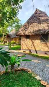 een stenen gebouw met een rieten dak en een tuin bij Kikambala Eco Villas in Mombasa