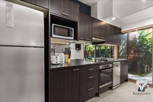 a kitchen with wooden cabinets and a refrigerator at KozyGuru | Spring Hill | Cosy 1 Bed1Bath in Brisbane