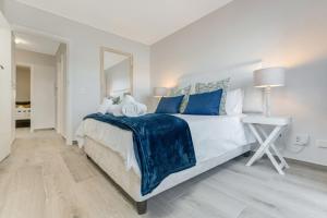 a white bedroom with a large bed with blue pillows at Vista Laguna in Knysna