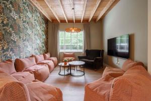 uma sala de estar com sofás laranja e uma televisão em Hulstehof em Zarren