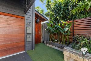 a house with a wooden garage door and green grass at KozyGuru | Spring Hill | 2 Bed 2.5 Bath in Brisbane +11 photos