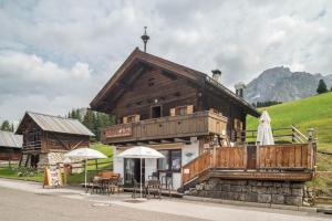 a large wooden building with tables and chairs in front of it at Baita Pecol Passo Pordoi in Canazei