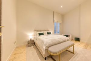 - une chambre blanche avec un lit et une chaise dans l'établissement Appartement dans l'hypercentre, à Bruxelles