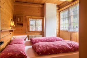 Duas almofadas vermelhas sentadas numa cama num quarto em Baita Pecol Passo Pordoi em Canazei