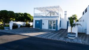 a white building with a blue door on a street at Starfish Cottage, Langebaan in Langebaan