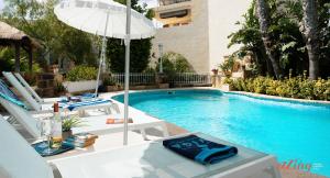 uma piscina com uma mesa e um guarda-sol em Rest, restore, explore. An exclusive stay in Malta em Żebbuġ