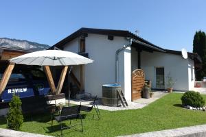 um pátio com um guarda-sol e cadeiras e uma casa em Bungalow Baloo Ferienhaus em Sankt Johann in Tirol