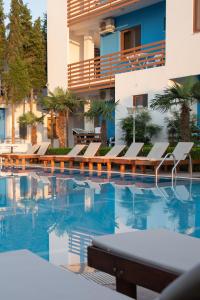 a swimming pool with chairs and a building at Hotel Athina in Velipojë