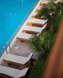 una fila de tumbonas junto a una piscina en Hotel Athina, en Velipojë