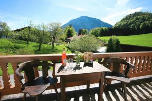 a wooden table with two chairs on a deck with mountains at Maurerhof in Ruhpolding