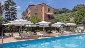a pool with chairs and umbrellas next to a building at La casa del Gallo in Pietra Ligure
