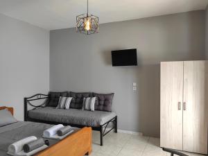 a bedroom with a bed and a couch and a tv at Anthos Rooms Vrasna in Nea Vrasna