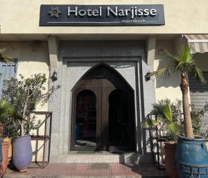 a hotel entrance with a palm tree in front of it at Hôtel Narjisse in Marrakesh