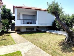 a white house with a tree in front of it at Anthos Rooms Vrasna in Nea Vrasna