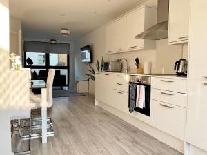 cocina con armarios blancos y fogones en Spacious 3 bed 3 bath Duplex Apartment - 18 mins from Central London - Sleeps 8, en Watford