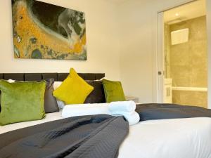 1 dormitorio con 1 cama con almohadas amarillas y verdes en Spacious 3 bed 3 bath Duplex Apartment - 18 mins from Central London - Sleeps 8, en Watford