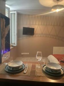 einen Tisch mit zwei Tellern und Weingläsern darauf in der Unterkunft Appartement style hôtel cocooning in Limoges