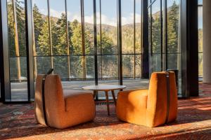 two chairs and a table in a room with windows at Hotel Nomad in Bjelašnica