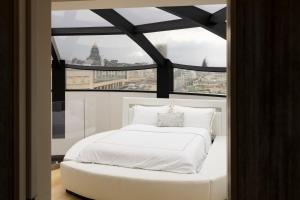 a white bed in a room with a large window at Triplex penthouse in the city center in Brussels