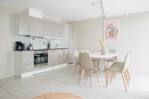 a white kitchen with a table and chairs at Nordic Nights: 3BR with Balcony in Bergen