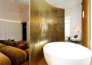 a bathroom with a tub and a gold wall at Montebelo Vista Alegre Lisboa Chiado Hotel in Lisbon +58 photos