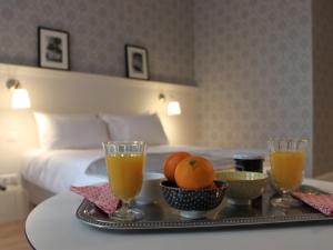 リモージュにあるLa Maison Blanche - AppartHôtels climatisés de charme Chic & Cosy - Centre-villeのホテルの客室のテーブルにフルーツとドリンクのトレイを用意しています。