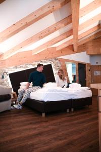 a man and woman sitting on a bed in a room at Wellness Hotel Lupo Bianco in Canazei
