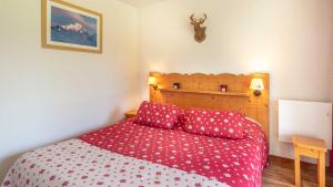 Schlafzimmer mit einem Bett mit roter Bettwäsche und einem Kopfteil aus Holz in der Unterkunft V du Bachat Arolles A03 - Appt 4 pers in Chamrousse