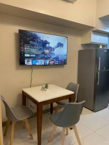 a kitchen with a table and chairs and a television at Cozy 1 BR One Uptown Residences BGC in Manila