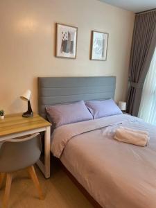 a bedroom with a bed and a desk with a lamp at Cozy 1 BR One Uptown Residences BGC in Manila