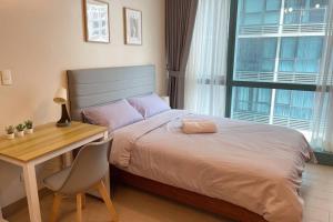 a bedroom with a bed and a table and a desk and a chair at Cozy 1 BR One Uptown Residences BGC in Manila