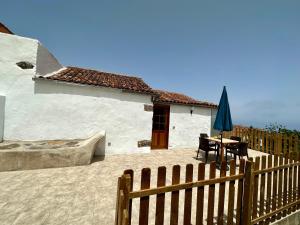 ein Haus mit einem Holzzaun, einem Tisch und einem Regenschirm in der Unterkunft Chozos Ocean View by VV Canary Ocean Homes in Las Cruces