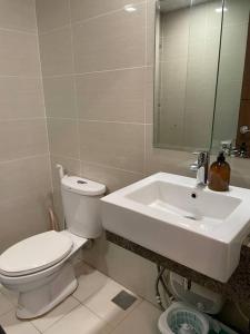 La salle de bains est pourvue de toilettes et d'un lavabo. dans l'établissement Cozy 1 BR One Uptown Residences BGC, à Manille