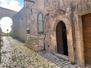 um antigo edifício de pedra com duas portas e uma rua de calçada em Terra della Baronia em Santo Stefano di Sessanio