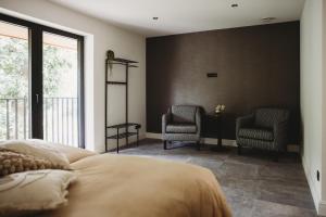 ein Schlafzimmer mit einem Bett und zwei Stühlen in der Unterkunft Eikenhoef in Lommel