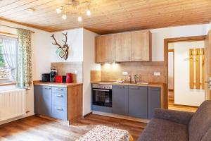 uma cozinha com armários azuis e um sofá num quarto em Ferienwohnung - Hexi em Bad Kohlgrub