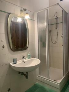y baño con lavabo y ducha con espejo. en Caratteristico appartamento nel borgo medievale en Castiglione della Pescaia