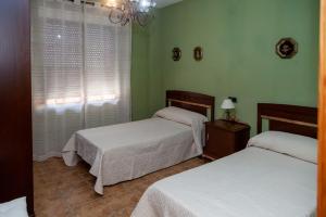 a bedroom with two beds and a window with a chandelier at Los olivares de Rober in Polán