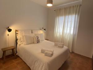 Un dormitorio con una cama blanca con toallas. en V V El Cantil, en Valverde